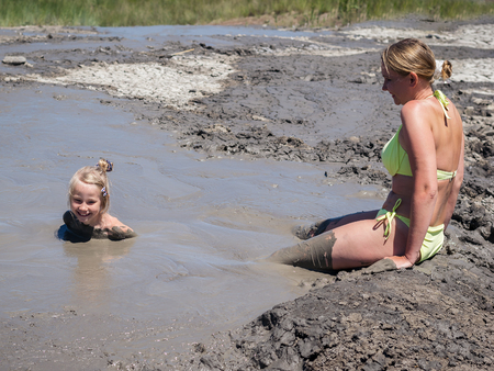 Mother gently bathing my daughter in the mud. Treatment non-traditional methods.の写真素材