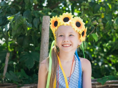 Portrait of beautiful girl with flowers of sunflowers on his head. The concept of a happy carefree childhood.の写真素材