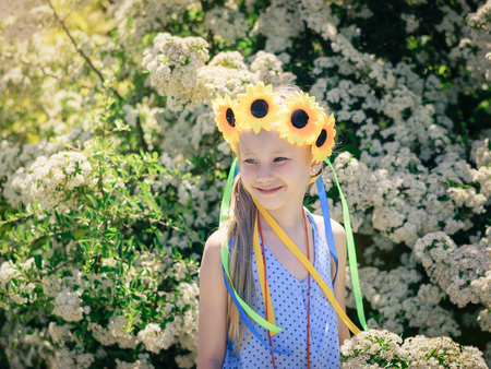 Portrait of beautiful girl with flowers of sunflowers on his head. The concept of a happy carefree childhood.の写真素材