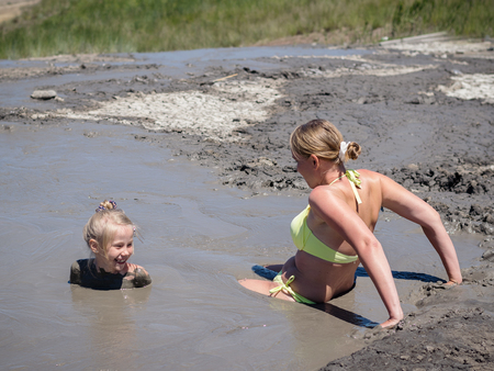 Mother gently bathing my daughter in the mud. Treatment non-traditional methods.の写真素材
