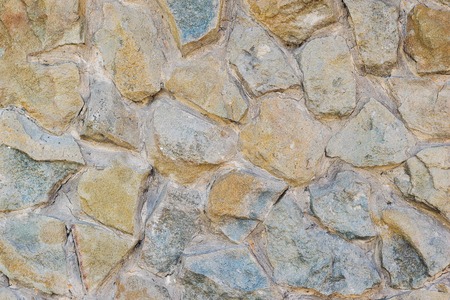A fragment of an artificially made wall of stone and binder solution. Background of stone wall.の写真素材