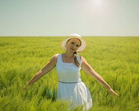 Portrait of a beautiful woman on a hot summer day on a field of green rye. Picture of beautiful woman in a beautiful field.の写真素材
