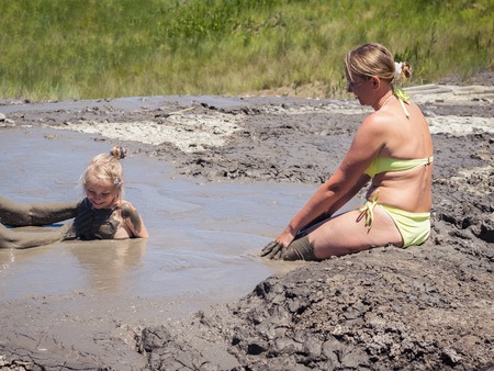 Mother gently bathing my daughter in the mud. Treatment non-traditional methods.の写真素材