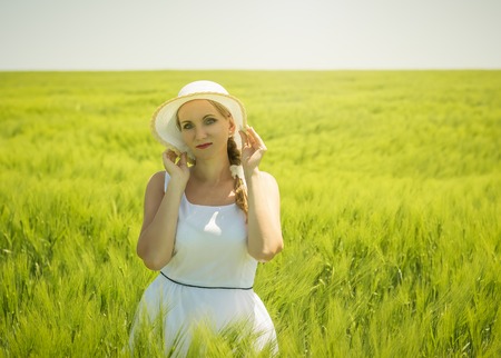 Portrait of a beautiful woman on a hot summer day on a field of green rye. Picture of beautiful woman in a beautiful field.の写真素材