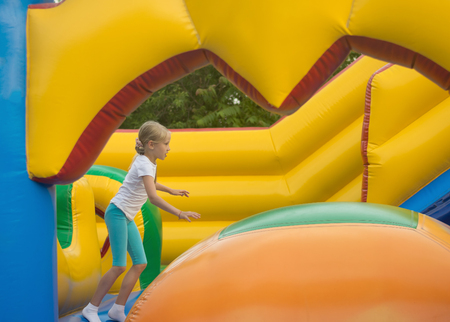 Little girl fun fun on an inflatable trampoline. The concept of a happy childhood.の写真素材