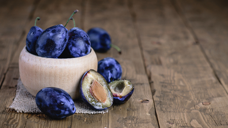 Ripe plums in bowl on wooden vintage table. The concept of a healthy vegetarian diet.の写真素材