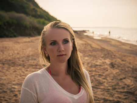 Beautiful woman in white clothes enjoying the sunset on the beach. Portrait of a beautiful woman by the sea.の写真素材