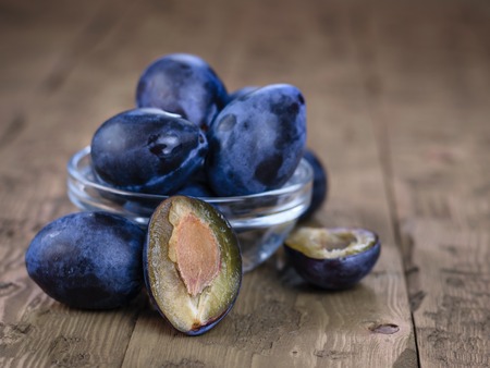 Ripe plums in bowl on wooden vintage table. The concept of a healthy vegetarian diet.の写真素材