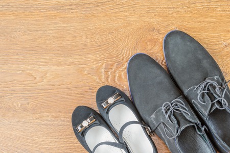 Classic men's boots and shoes girls on the wooden floor top view. The concept of friendship in the family.の写真素材