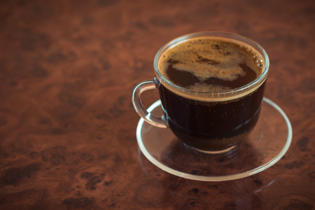 A Cup of freshly brewed coffee on a brown table. Photo of coffee in a glass container.の写真素材