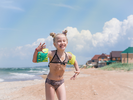 Girl with beautiful hairstyle fun playing by the sea on a Sunny day. The concept of happy summer days hanging out by the sea.の写真素材