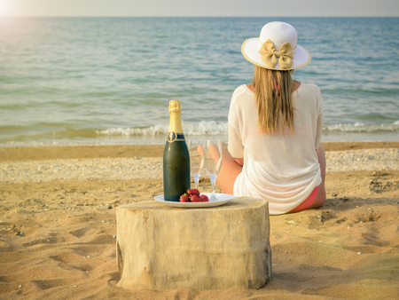 A full bottle of shaman's, strawberries and the woman on the beach. The concept of a happy holiday on the shores of the sea.の写真素材