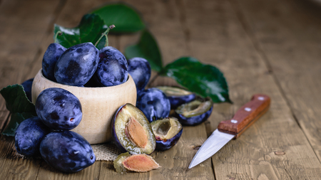 Ripe plums in bowl on wooden vintage table. The concept of a healthy vegetarian diet.の写真素材