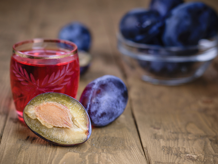 Bright red the aperitif of plum on a wooden table.の写真素材