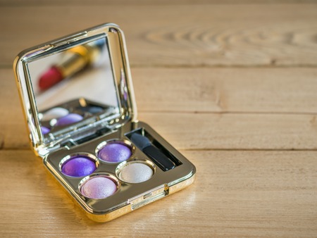 Eye shadow and reflected in the mirror lipstick on a vintage wooden table.の写真素材
