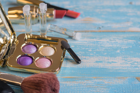 Eyeshadow, brush, lipstick on a vintage wooden table. Set of beautiful women's cosmetics on the table.の写真素材