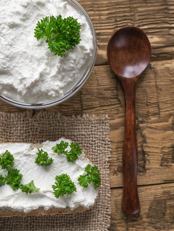 A fresh slice of bread smeared with cottage cheese cream with parsley on the table. The concept of a healthy diet. View from above.の写真素材