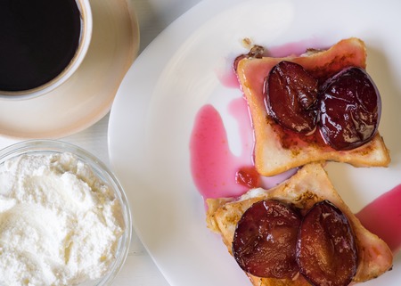 Two pieces of French bread with plum jam, with coffee, orange curd cream. Top view.