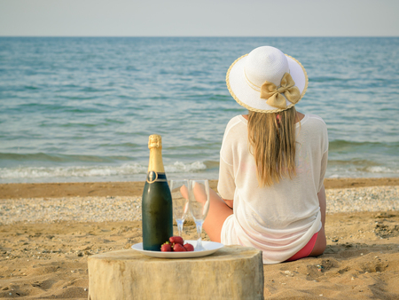 A full bottle of shaman's, strawberries and the woman on the beach. The concept of a happy holiday on the shores of the sea.の写真素材