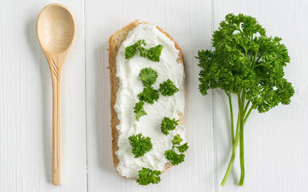A fresh slice of bread smeared with cottage cheese cream with parsley on the table. The concept of a healthy diet. View from above.の写真素材
