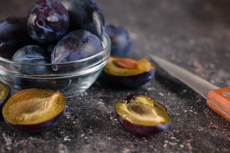 Ripe plums in a glass bowl on the stone table top view. The concept of a good harvest of plums.の写真素材