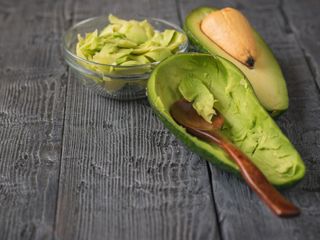 The flesh of the avocado in a glass bowl on a wooden table with a spoon. Vegetarian food. The concept of a healthy lifestyle.の写真素材