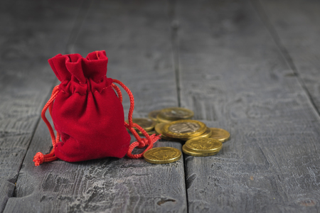Red velvet pouch with coins on a wooden vintage table. The concept of saving money.の写真素材