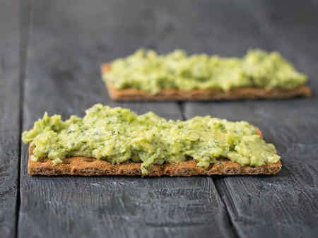 Fresh crisp bread with cream and avocado on a rustic table. The dish is vegetarian diet. Diet for weight loss.の写真素材