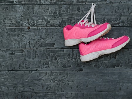 A pair of pink sport shoes on the background of a wooden wall. The concept of sports lifestyle.の写真素材