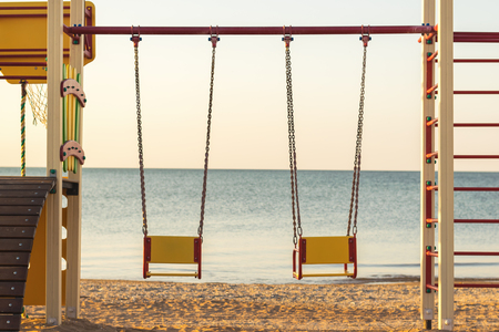 Swings on chains for two on the background of evening sunset sea. The concept of a romantic evening for lovers.の写真素材