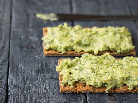 Fresh crisp bread with cream and avocado on a rustic table. The dish is vegetarian diet. Diet for weight loss.の写真素材
