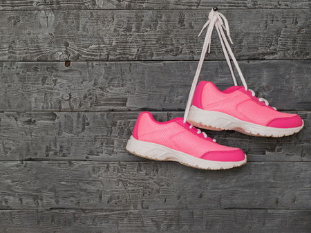 A pair of pink sport shoes on the background of a wooden wall. The concept of sports lifestyle.の写真素材