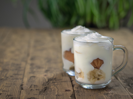 Banana pudding with cookies decorated with whipped cream on a wooden table.の写真素材