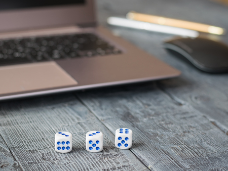 Dice with blue dots, notebook and pens on a wooden table.の写真素材