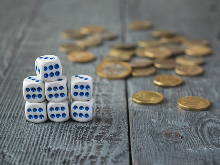 Seven dice and the metal coins on a wooden table.の写真素材