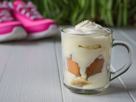 Banana pudding on a wooden table and pink women sneakers in the background. Sports nutrition.の写真素材