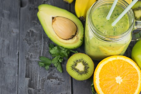 A freshly prepared smoothie of avocado, banana, orange, lemon and kiwi on a wooden table. Diet vegetarian food. Raw foods.の写真素材