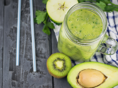 A freshly prepared smoothie of avocado, banana, orange, lemon and kiwi on a wooden table. Diet vegetarian food. Raw foods.の写真素材