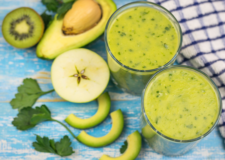 A freshly prepared smoothie of avocado, banana, orange, lemon and kiwi on a wooden table. Diet vegetarian food. Raw foods.の写真素材