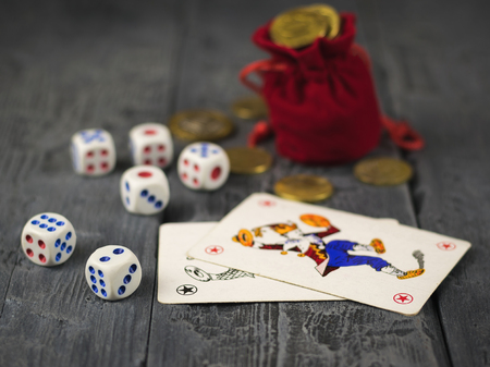 Dice, playing cards and a red money bag on a wooden table. The concept of gambling.の写真素材