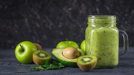A freshly prepared smoothie of avocado, banana, orange, lemon and kiwi on a wooden table. Diet vegetarian food. Raw foods.の写真素材