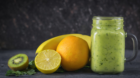 A freshly prepared smoothie of avocado, banana, orange, lemon and kiwi on a wooden table. Diet vegetarian food. Raw foods.の写真素材