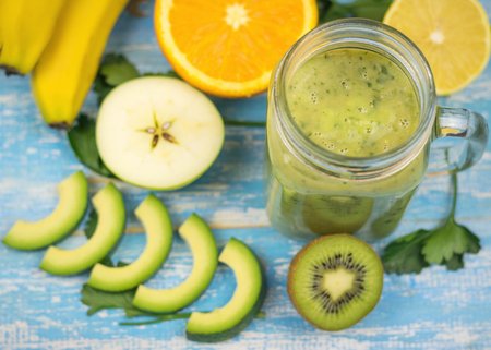 A freshly prepared smoothie of avocado, banana, orange, lemon and kiwi on a wooden table. Diet vegetarian food. Raw foods. Top view.の写真素材