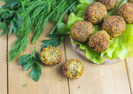 Freshly cooked falafel on lettuce leaves on a dark wooden table with tahini sauce. Eastern vegetarian meal of chickpea.の写真素材