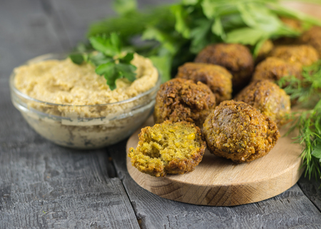 Freshly cooked falafel on lettuce leaves on a dark wooden table with tahini sauce. Eastern vegetarian meal of chickpea.の写真素材