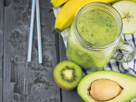 A freshly prepared smoothie of avocado, banana, orange, lemon and kiwi on a wooden table. Diet vegetarian food. Raw foods.の写真素材