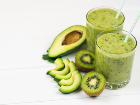 A freshly prepared smoothie of avocado, banana, orange, lemon and kiwi on a white wooden table. Diet vegetarian food. Raw foods. Top view.の写真素材