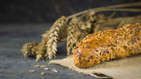 Freshly prepared baguettes on a piece of burlap on a dark table with ears. Background of ripe wheat ears.の写真素材