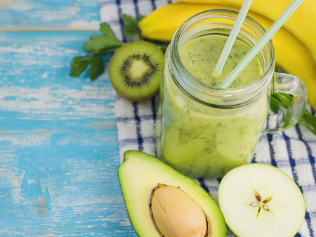 A freshly prepared smoothie of avocado, banana, orange, lemon and kiwi on a wooden table. Diet vegetarian food. Raw foods. Top view.の写真素材