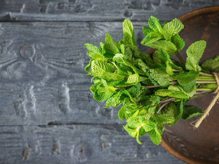 A bundle of fresh cut mint on a dark rustic table. The concept of healthy eating. The use of herbs.